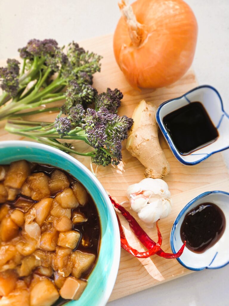 A display of the ingredients used for this recipe: marinaded chicken, soy sauce, oyster sauce, garlic, chili, ginger, broccoli, onion