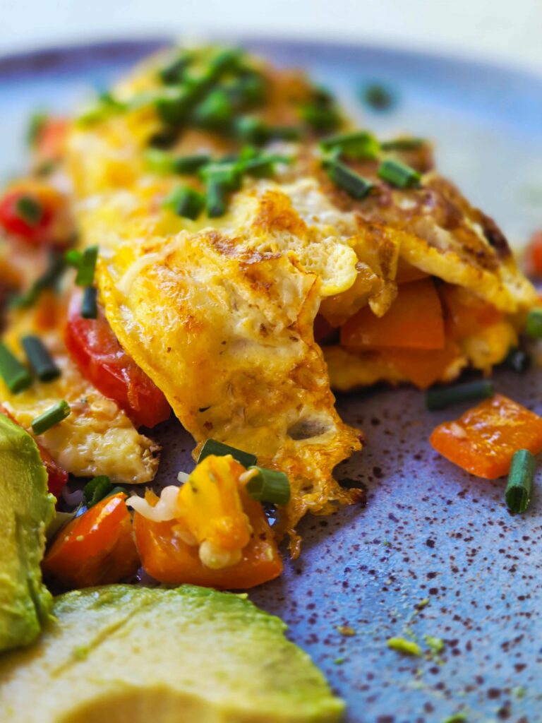 front of the omelette showing the peppers and tomatoes inside