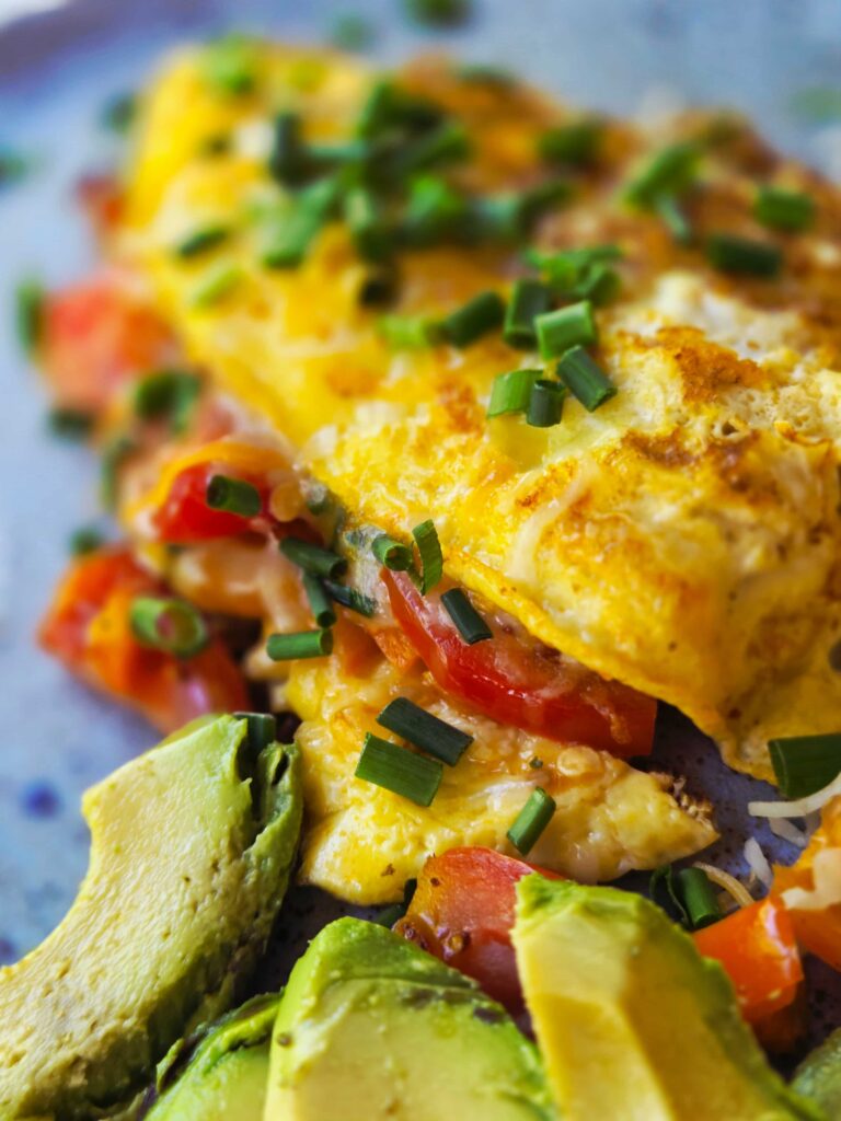 An omelette with avocado, tomatoes, and peppers, and cheese